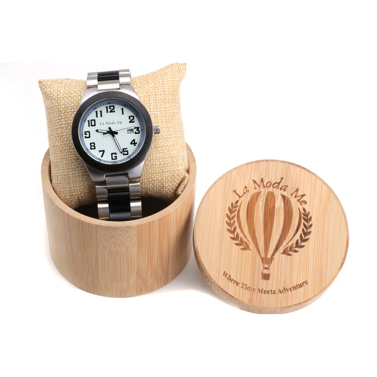 Wristwatch with a white dial and bold black numerals, presented on a cushion inside a bamboo gift box. The watch features a black and silver metal strap, and the box lid is engraved with the “La Moda Me” logo and the phrase “Where Time Meets Adventure”.